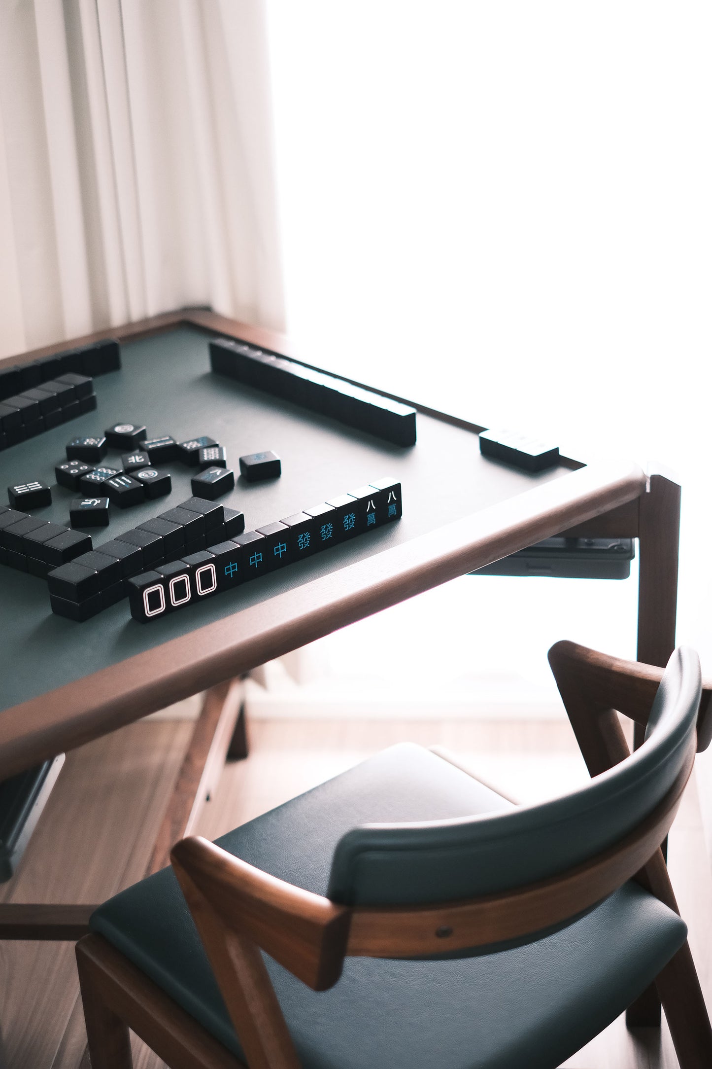 MJ88 Foldable Mahjong Dining Table – setup with black tiles, score counter, and wooden chair in natural light 麻雀餐桌,日本製,擺放黑色麻雀牌與記分器,搭配原木椅子,自然光下溫馨氛圍。