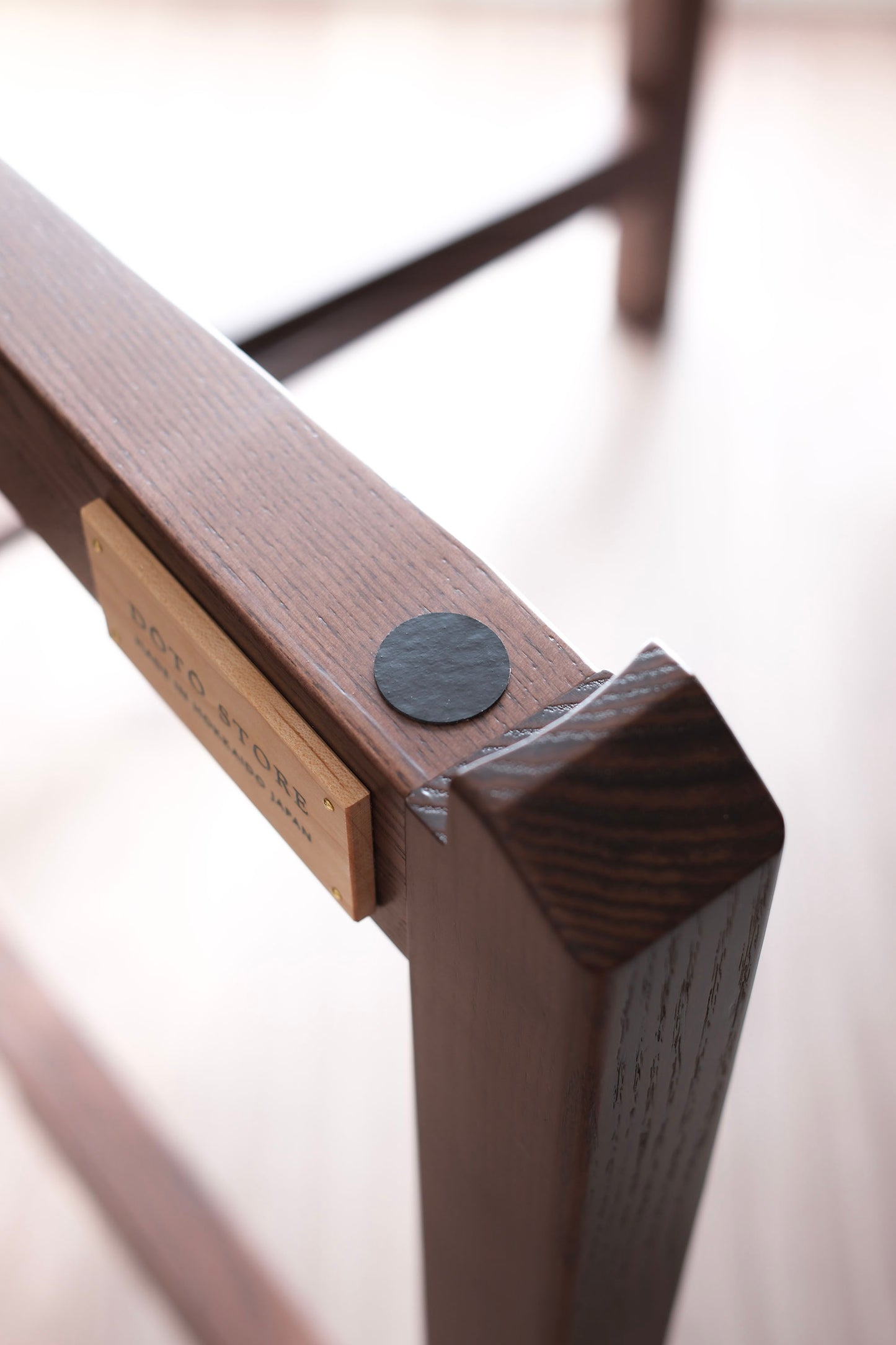 MJ88 Mahjong Dining Table – close-up of leg structure with DOTO STORE brand tag, showcasing refined wood joinery and inner edge craftsmanship. 麻雀餐桌桌腳內側特寫,搭配 DOTO STORE 品牌木牌,展現細膩木作工藝與穩固結構。