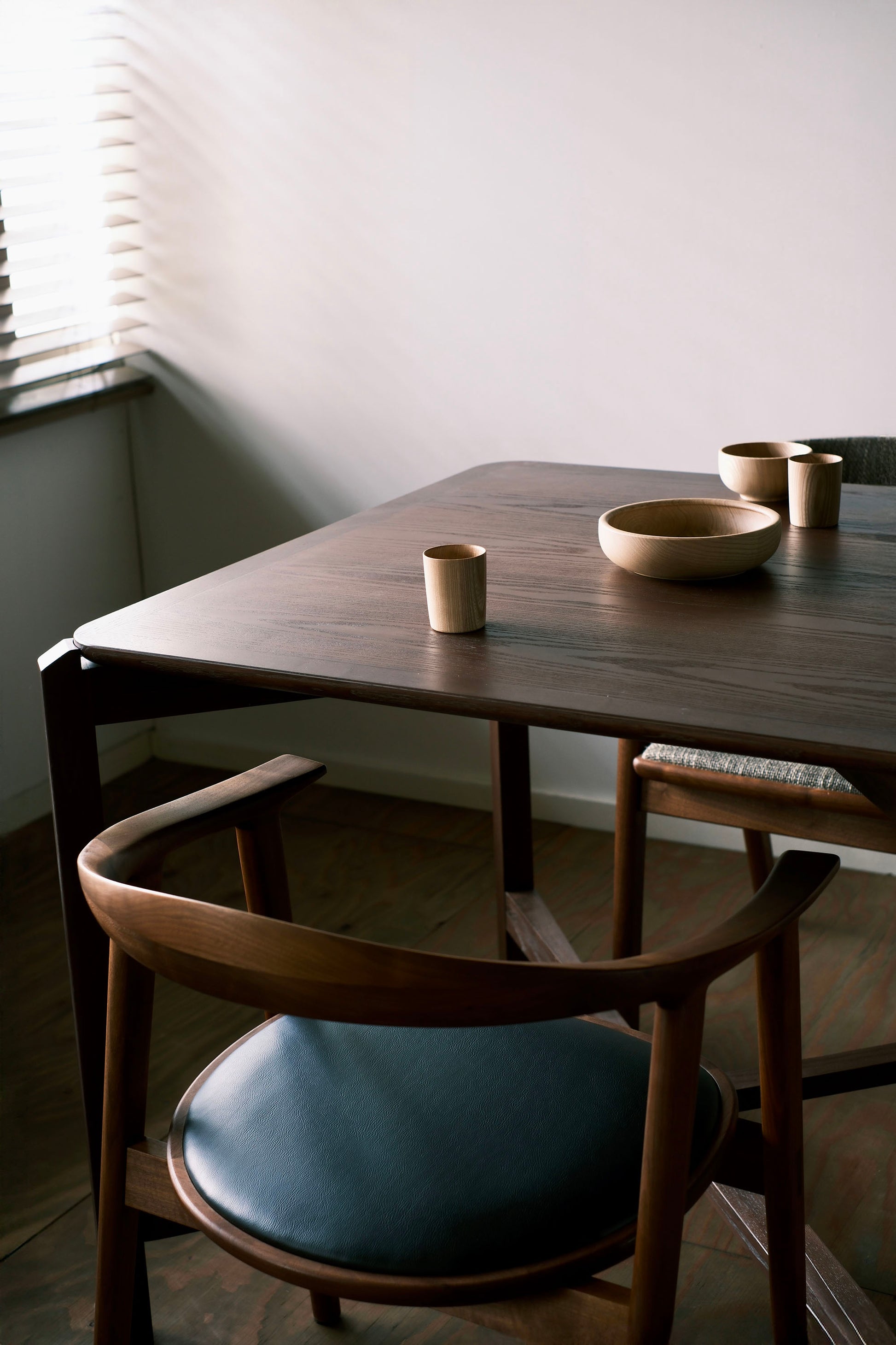 MJ88 Foldable Mahjong Dining Table – close-up of dining setup with soft light, ceramic bowls, and curved wooden chair in a modern minimalist interior 麻雀餐桌,日本製,特寫柔光下的餐桌角落,搭配陶瓷餐具與曲木椅,展現簡約空間的生活美感。
