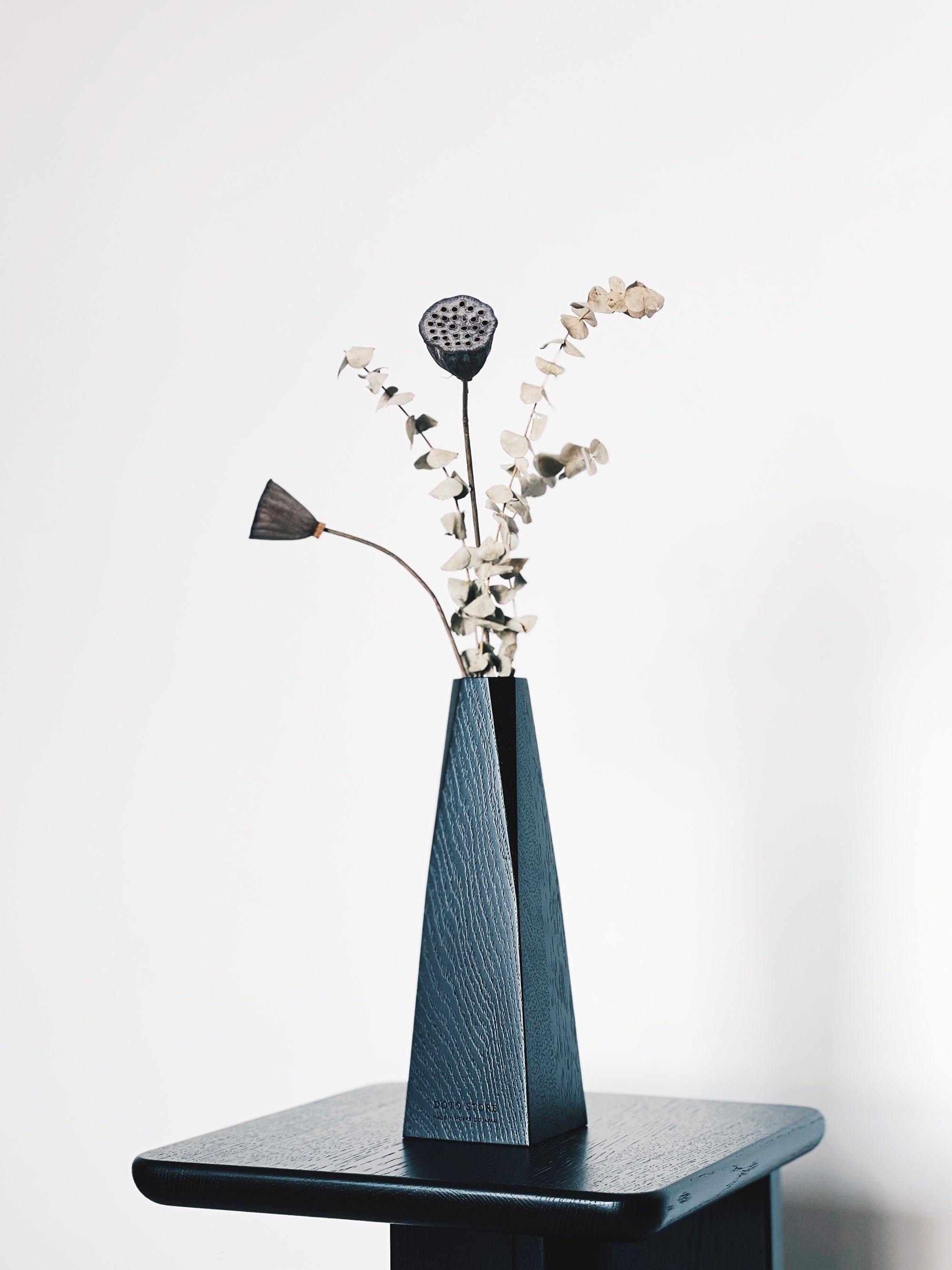 Black wooden vase with dried flowers on matching side table 黑色木製花瓶搭配乾燥花，擺放於同色系邊桌上