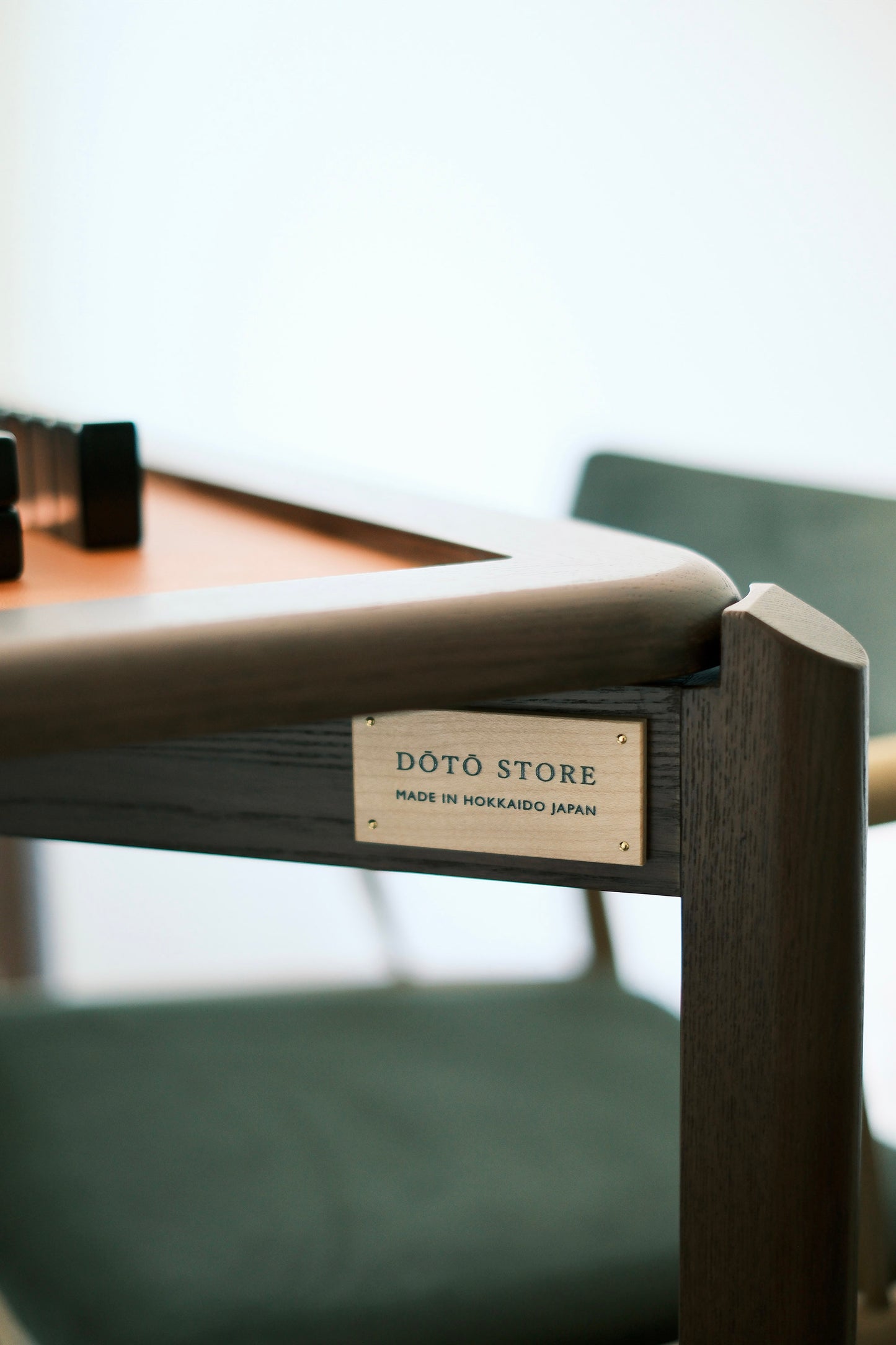 Doto Store maple wood logo plate reading Made in Hokkaido Japan on the MJ88R mahjong table edge
MJ88R 麻雀桌側嵌有 Doto Store 銅製標牌，標示日本北海道製造