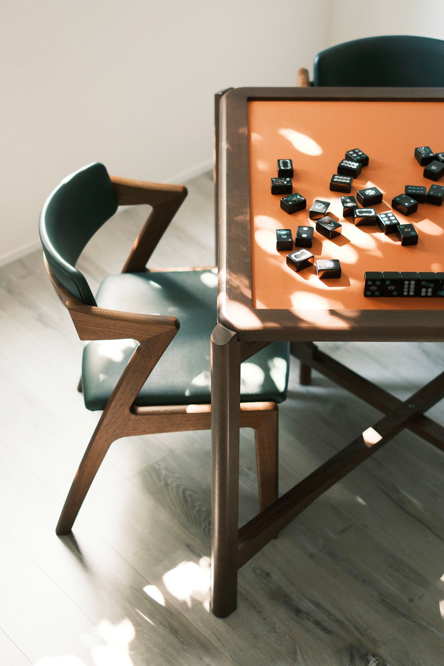 MJ88R foldable mahjong dining table with black tiles and a green upholstered chair in natural light
MJ88R 摺疊麻雀餐桌配黑色麻雀牌與綠色軟墊餐椅，自然光下拍攝