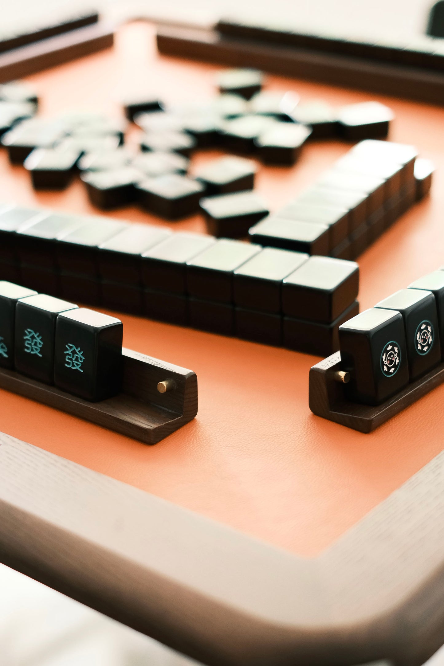 Wooden mahjong tile racks holding black Hokkaido-theme tiles on the MJ88R table's leather surface.
木製麻雀牌尺承托黑色北海道主題麻雀牌，置於 MJ88R 皮革桌面